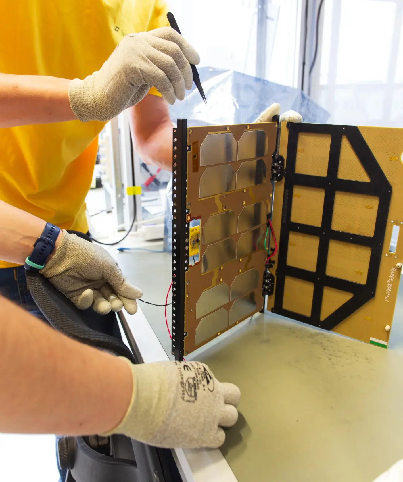 Engineer assembling a CubeSat solar panel in a cleanroom