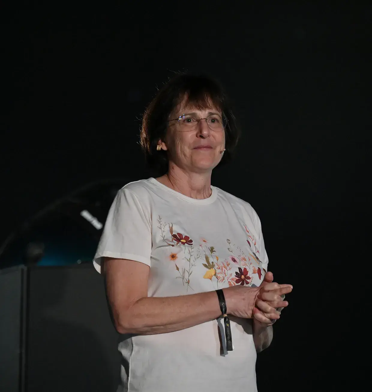 Speaker presenting on a dark stage at a space conference