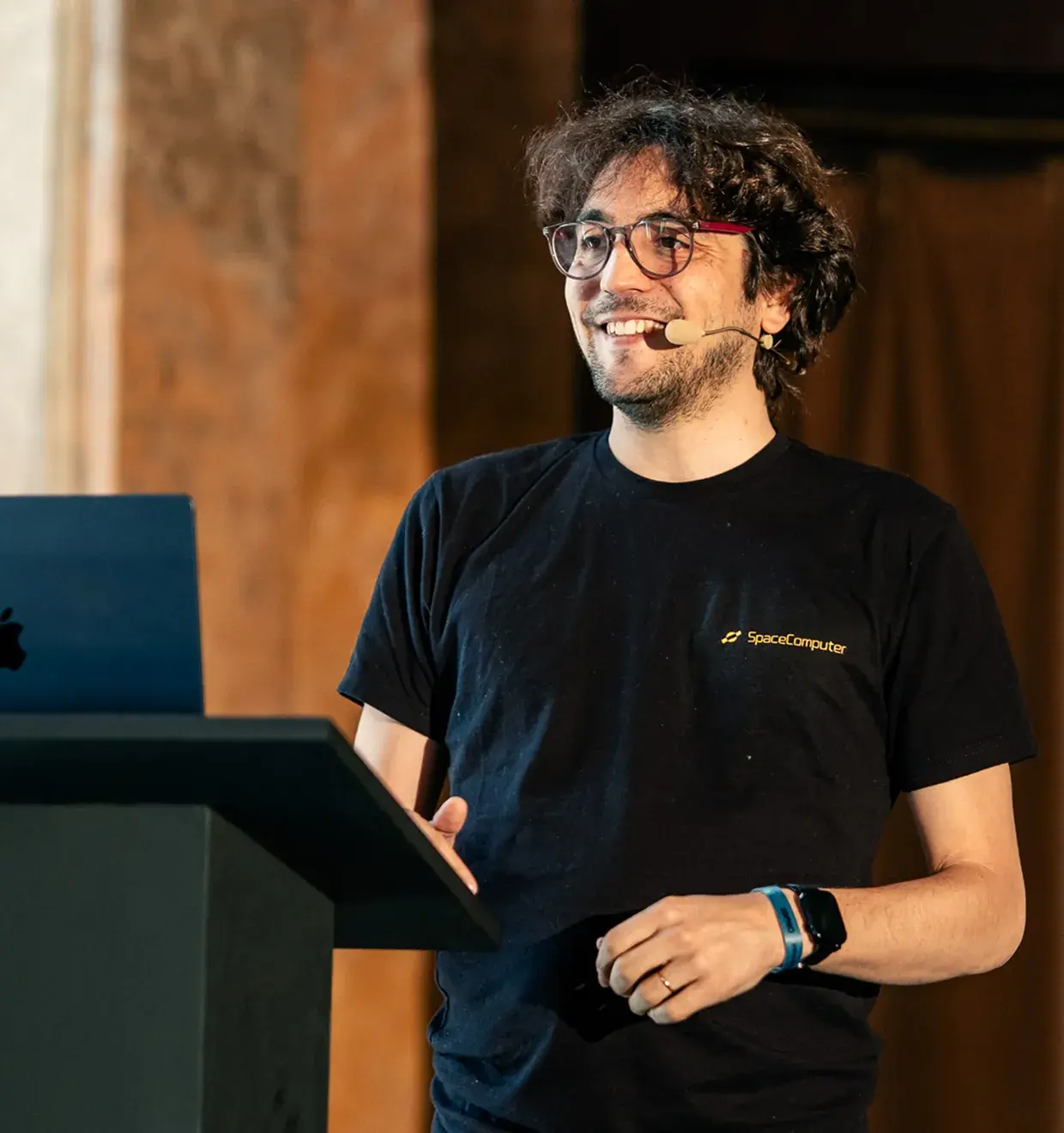 SpaceComputer team member presenting at a podium with a headset microphone
